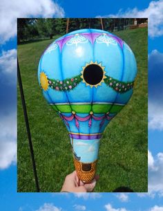 a hot air balloon being held up in the air by someone's hand with a sky background