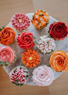 cupcakes decorated with colorful flowers on a marble platter, top view from above