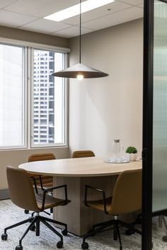 an empty conference room with chairs and a round table in front of a large window