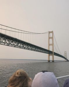 two people sitting on a boat looking at the bridge