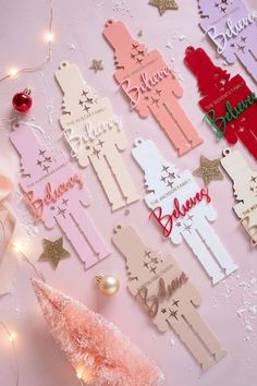 some pink and red paper cutouts on a table with christmas decorations around them,