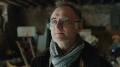 a man with glasses and a scarf around his neck looking off to the side in a garage