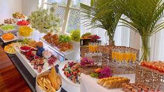 an assortment of food and drinks on display at a buffet or wedding reception with palm trees in the background