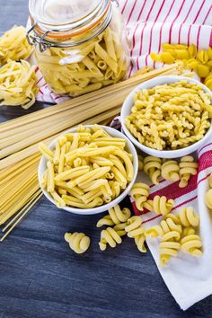 three bowls filled with pasta next to some noodles