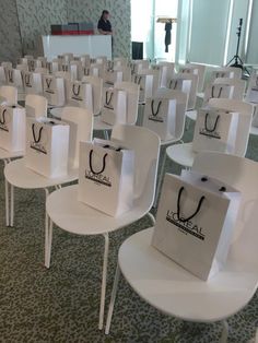 many white chairs with bags on them sitting in a room filled with tables and chairs