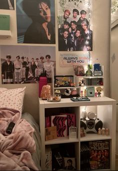 a bedroom with posters on the wall and a book shelf in front of it's bed