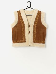 Rare 70s vintage embroidered Afghan sheepskin vest. This very rare 1970s beautiful tan suede features yellow embroidery around the opening and back, two open side pockets, a toggle closure and a V-neck. Made from a heavyweight butter soft suede and a cosy sheepskin lining. Our recommended size: Medium to large Label says: No size label  Condition: Good* Some light, natural rubbing. Please see last image (not colour accurate) Material: No care label, confident it is suede Lining: No care label, c Vintage Sleeveless Outerwear For Festivals, Winter Festival Outerwear Vest, Vintage Beige Winter Vest, Winter Bohemian Brown Vest, Bohemian Brown Winter Vest, Sherling Vest, Brown Bohemian Winter Vest, 70s Knit Vest, 70s Suede Jacket