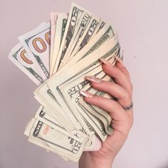 a woman's hand holding money in front of her face