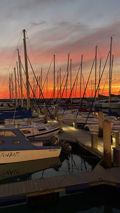 many boats are docked in the water at sunset