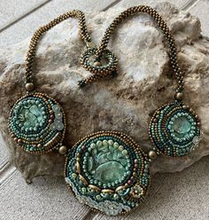 a necklace and earrings sitting on top of a rock next to a stone slab with beads