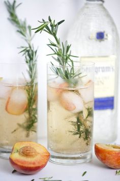 an apple and rosemary garnish in two glasses next to a bottle of gin