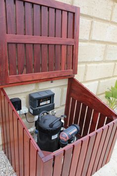 an open wooden box with tools in it on the ground next to a brick wall