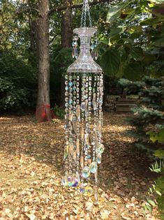 a crystal chandelier hanging from a tree in the yard with leaves on the ground