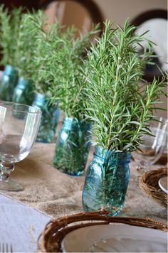 a table topped with blue glass vases filled with greenery