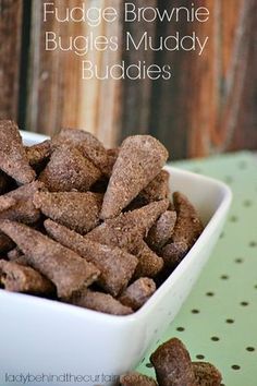 chocolate fudge brownie muddy buddies in a white bowl on a green tablecloth