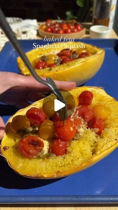 a person cutting into a dish with tomatoes and olives in it on a blue tray