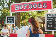 a woman standing in front of a hot dog stand