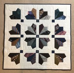 a quilted wall hanging with many different ties arranged in the shape of a flower