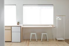 two white stools sit in front of a window