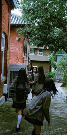 two girls are walking down the sidewalk with their backpacks on and one girl has her back to the camera