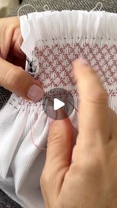 someone is stitching fabric with scissors on a piece of white material that has been sewn