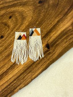 pair of white beaded fringe earrings on wooden surface