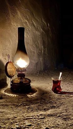 an old fashioned lamp sitting on top of a table next to a cup and a pipe