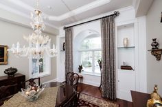 a dining room with a chandelier hanging from it's ceiling next to a window