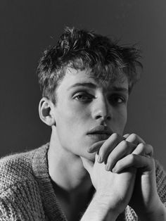 black and white photograph of a young man with his hand on his chin looking at the camera