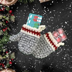 a knitted mitt with a christmas card in it on top of snow covered ground