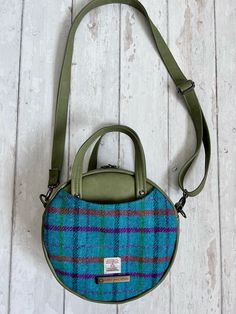 "Harris Tweed is a one-of-a-kind fabric, handwoven by individual artisans on Harris in the Outer Hebrides. Something this unique needs a handbag to match, and this circle handbag is just that! The certificate of authenticity is on the front. This bag is completely handmade in my sewing studio in Edinburgh, and the green faux leather is made from 100% recycled plastic.  Featuring grab handles, as well as a detachable adjustable crossbody strap, this circle handbag has two exterior slip pockets (the same front and back, to make the most of the tweed and a waterproof canvas lining to help fend off the worst of the Scottish weather with interior zip and slip pockets, making it easy to keep everything organised when you're out and about. Black nickel hardware and zips add the finishing touches Tweed Top Handle Shoulder Bag For Everyday, Everyday Tweed Shoulder Bag With Top Handle, Everyday Tweed Top Handle Shoulder Bag, Everyday Tweed Crossbody Bag, Circle Handbag, Harris Tweed Bag, Outlander Gifts, Tweed Bag, Circle Bag