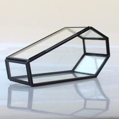 a glass box sitting on top of a white table next to a black object that is upside down