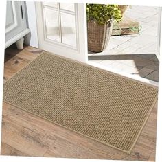 a close up of a door mat on the floor near a potted plant in a doorway