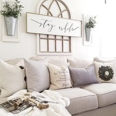 a living room filled with white furniture and lots of pillows on top of the couch