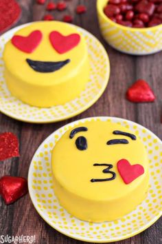 two yellow cakes decorated with red hearts and faces on white plates next to each other