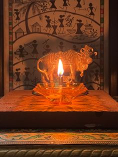 an animal shaped candle is lit in front of a wall with decorative designs on it