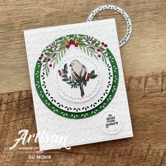 a christmas card with a bird on it and holly wreaths around the edges,