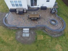 an aerial view of a patio with benches and fire pit in the middle of it