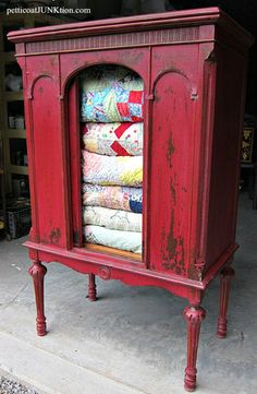 an old red cabinet with quilts in it