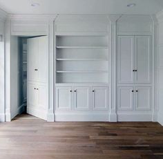 an empty room with white cupboards and wood flooring in the center is shown