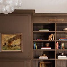 a bookshelf filled with lots of books next to a painting on the wall