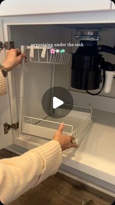 a woman is opening the refrigerator door to see what's in the dishwasher