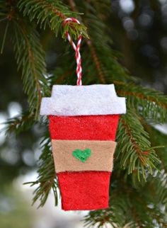 an ornament hanging from a christmas tree with a red cup on it's side