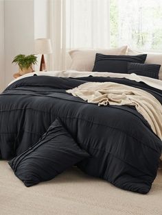 a bed with black comforter and pillows in a room