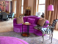 a living room with purple couches and zebra print pillows on the floor, chairs and tables in front of large windows