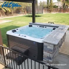 a hot tub sitting on top of a patio next to a fence