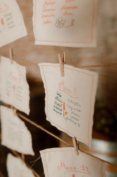 several pieces of paper hanging from clothes pins with writing on them and pinned to strings