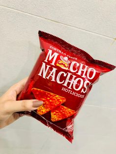 a person holding up a bag of nachos