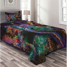 a bed covered in a colorful comforter next to a night time scene with lights