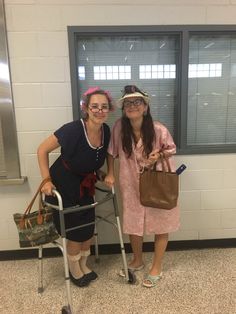 two women standing next to each other in front of a window holding shopping bags and crutches